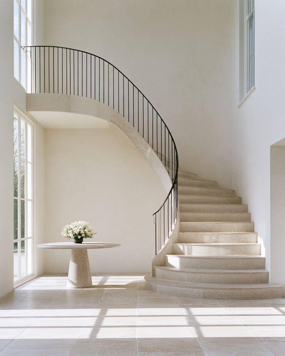 The entrance hall of a private residence with a stone staircase and white flowers
